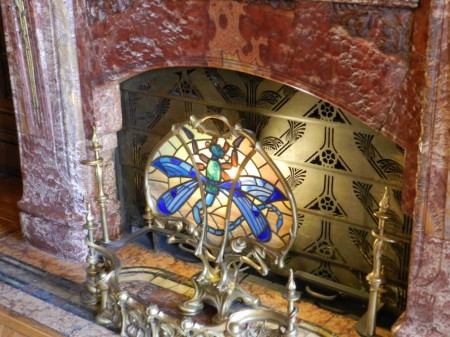 cheminée monumentale en onyx rouge. Pare-feu en cuivre découpé et vitrail à motif de libellule,