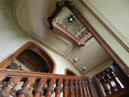 Grand escalier d'honneur : rampe à décor sculpté de branches et de pommes-de-pin.